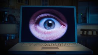 An image of a close-up of a human eye on lap top computer in a domestic kitchen, at night